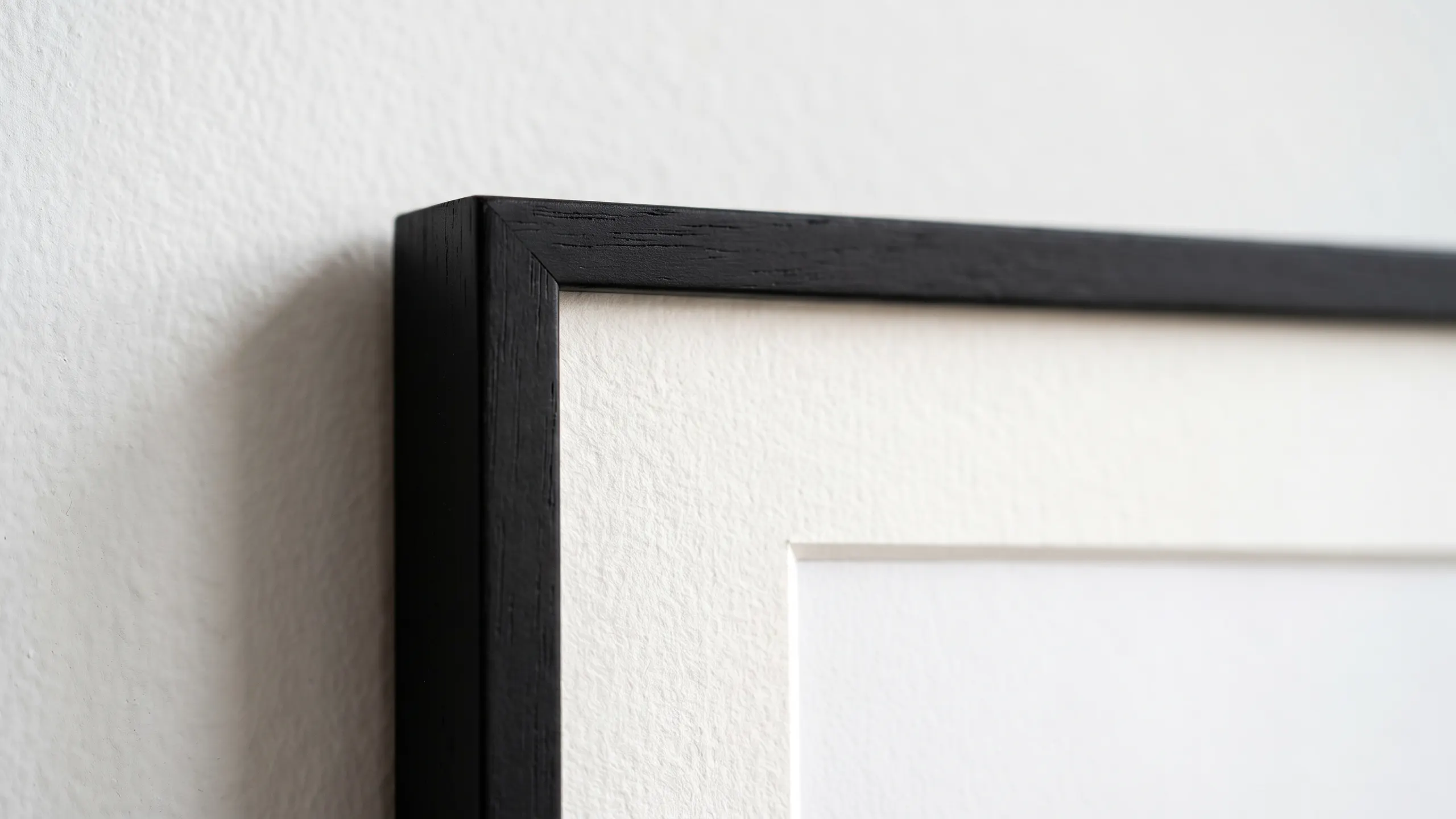 Corner of a matte black frame with archival mat on a gallery wall